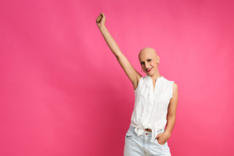 Optimistic woman after chemotherapy on pink background concept fights cancer